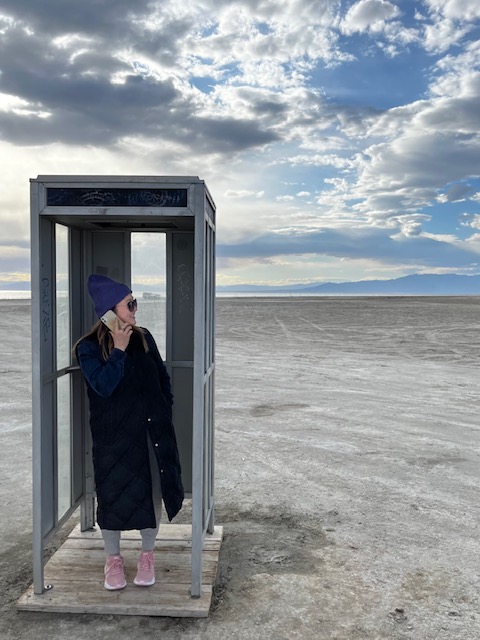 Photograph of Vivian in a phone booth located in a desert.